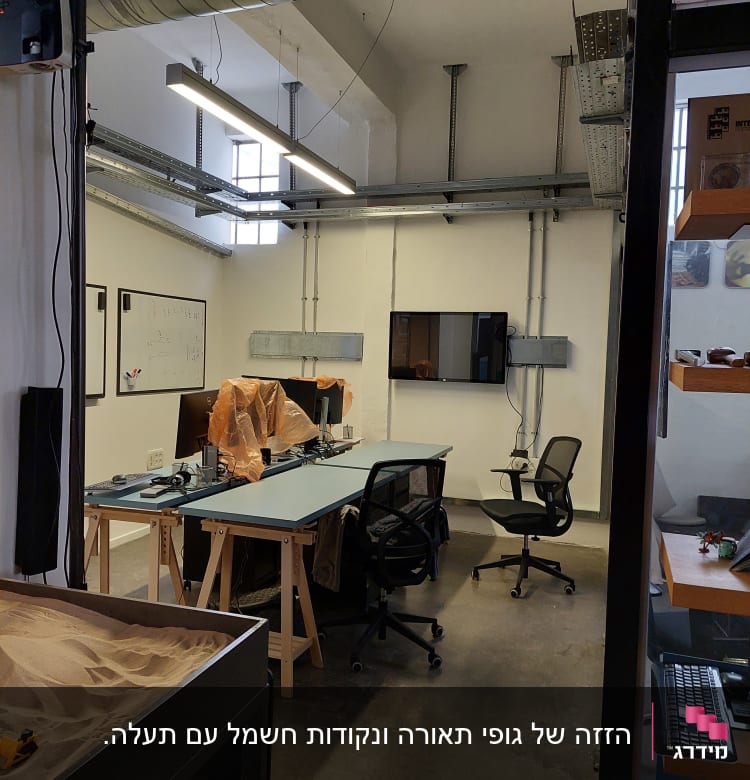 חדר עבודה עם שולחנות, כיסאות ותעלות חשמל בתקרה